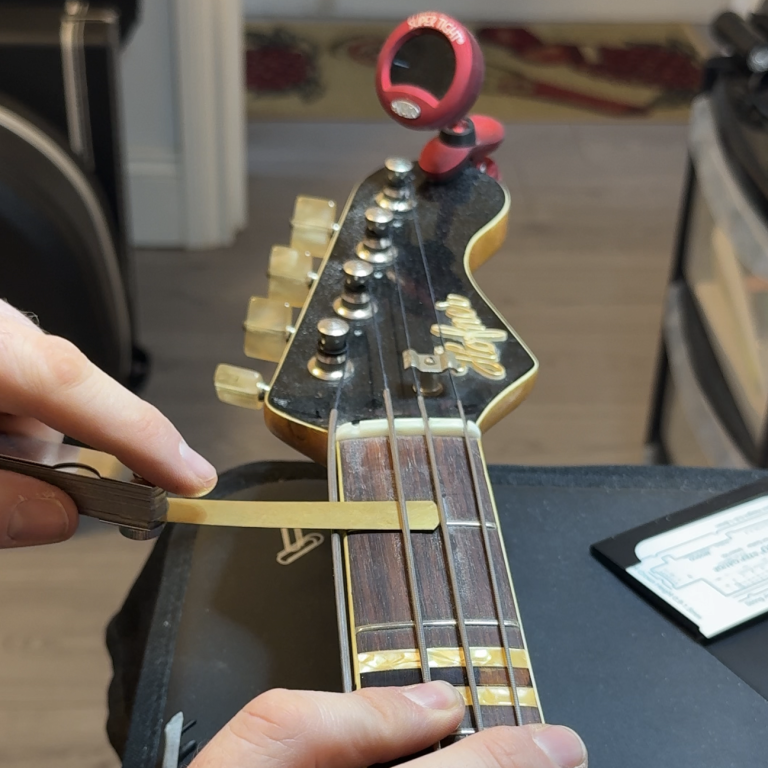Advanced setup and precision nut work Close-up of detailed nut adjustment during an advanced setup on a vintage bass to improve playability and tuning stability