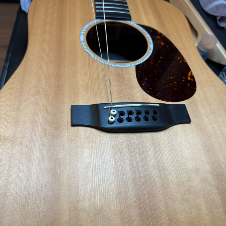 Acoustic guitar setup and servicing Acoustic guitar on the workbench during setup and servicing to improve playability and tone